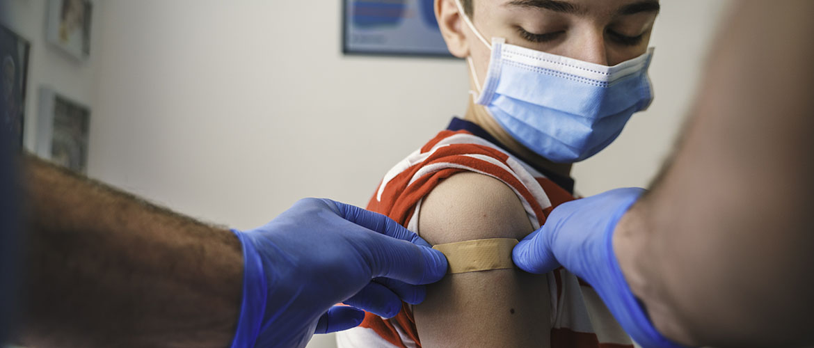 boy wearing mask gets routine childhood immunization