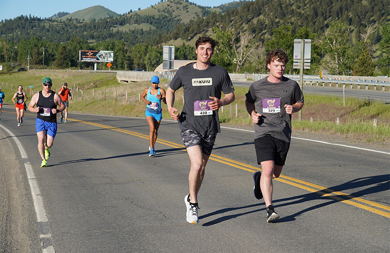 Two young men are among people running on a road